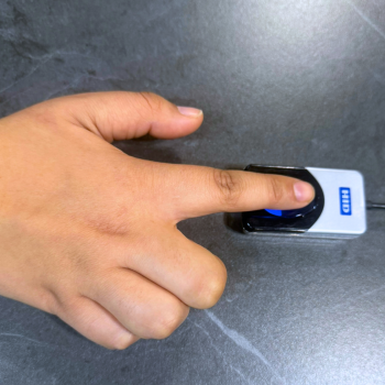 Paciente utilizando el sistema de huella digital de I-MED para bono electrónico en mesón de atención clínica