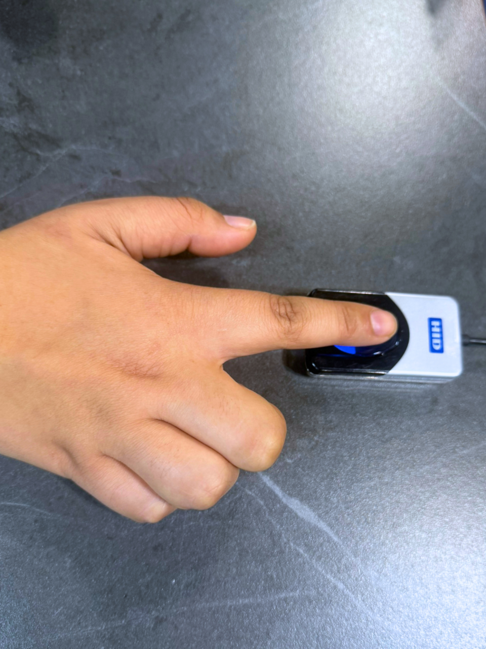 Paciente utilizando el sistema de huella digital de I-MED para bono electrónico en mesón de atención clínica